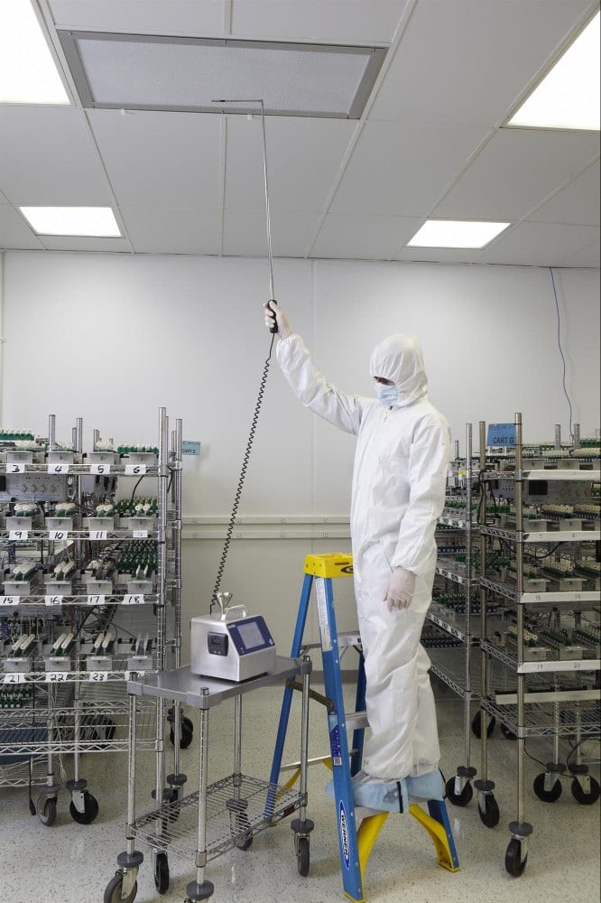 Technician performing air sampling with probe at HEPA filter in cleanroom – microbial monitoring
