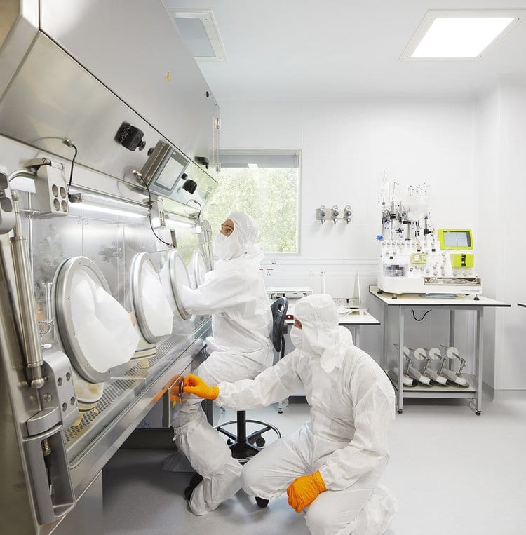 Two technicians at isolator in pharmaceutical cleanroom – GMP production with air monitoring