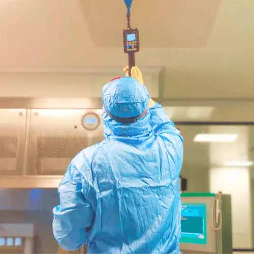 Technician with handheld particle counter in cleanroom – particle-free electronics production